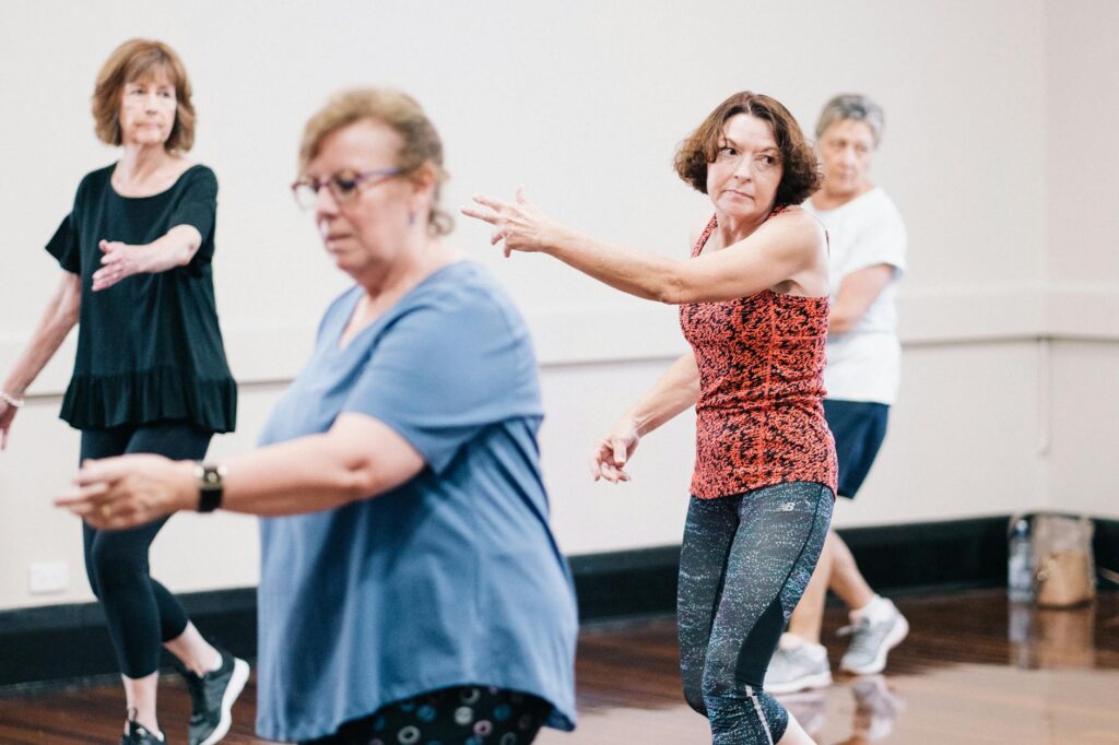 Senior women enjoying a group dance exercise in a fitness class, promoting health and togetherness.