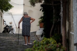 Mulher Que Caminha Enquanto Segura A Bengala Perto Da Arvore Alta 4podE_V_tAc