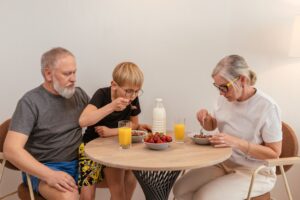 A family of three enjoying breakfast around a wooden table at home.