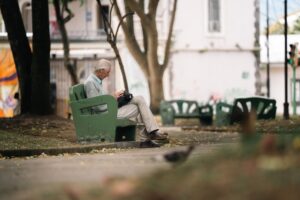 An elderly man sits quietly on a park bench in San José, Costa Rica, enjoying a peaceful day outdoors.