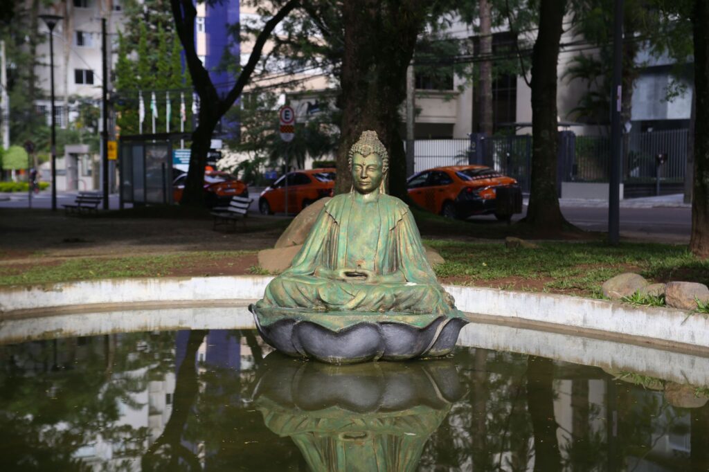 Buddha statue surrounded by a serene park setting in Curitiba, Brazil.