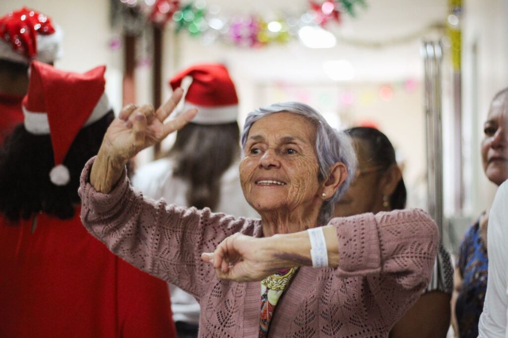 Joyful elderly woman celebrating indoors during a festive Christmas event.