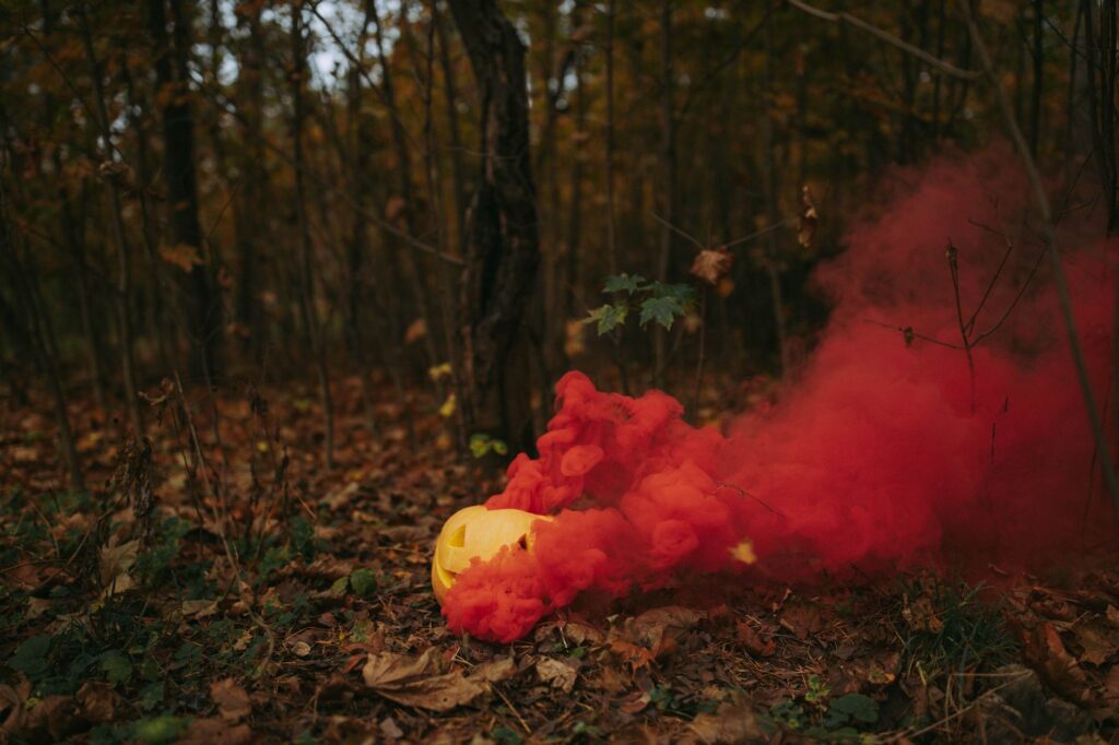 A mysterious forest setting with a Halloween pumpkin emitting colorful smoke.