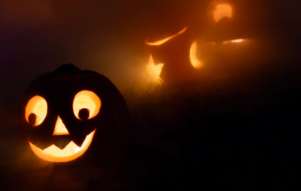 Eerie jack-o'-lanterns glowing in the fog, creating a spooky Halloween atmosphere.