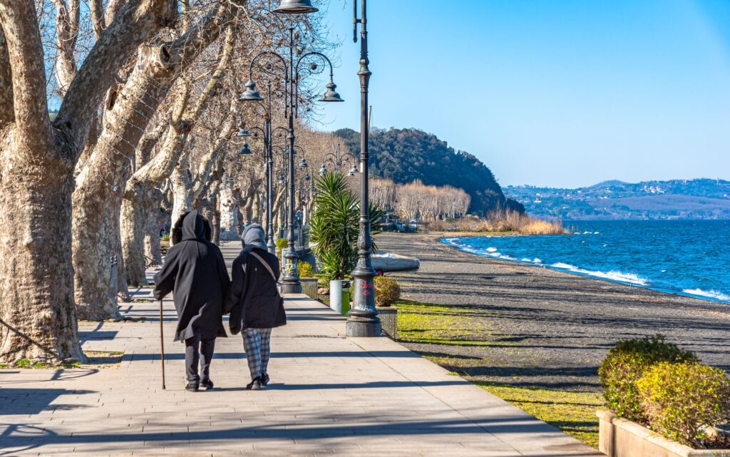 Two people strolling along Lake Bracciano's scenic walkway in winter, Lazio, Italy.