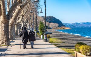 Two people strolling along Lake Bracciano's scenic walkway in winter, Lazio, Italy.