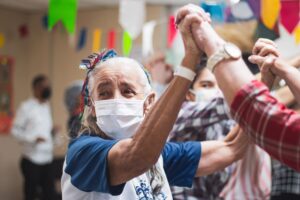 Senior adults celebrating together indoors with joyful dancing, fostering community spirit and happiness.
