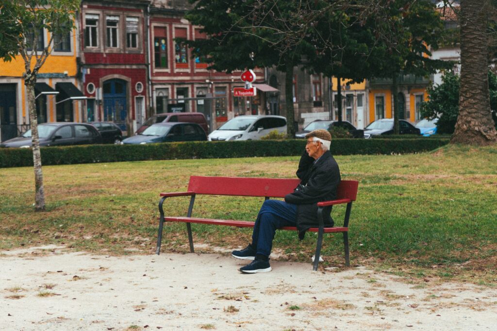An elderly man sitting on a bench in a scenic park in Porto, Portugal.