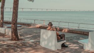 Man sitting on a bench overlooking Tagus River and Vasco da Gama Bridge in Lisbon.
