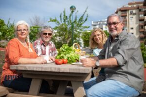 Happy group of seniors enjoying a picnic outdoors with fresh vegetables.