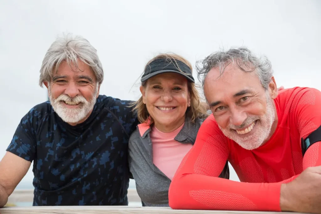 Senior friends in Portugal smiling and enjoying an outdoor fitness activity.