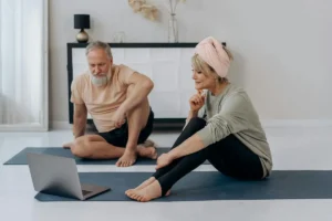 Elderly couple practicing yoga online at home, promoting wellness.