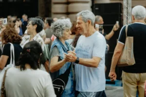 Senior couple dancing joyfully at an outdoor gathering, celebrating life and connection.