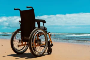 A wheelchair on a sandy beach overlooking the sea on a bright summer day.