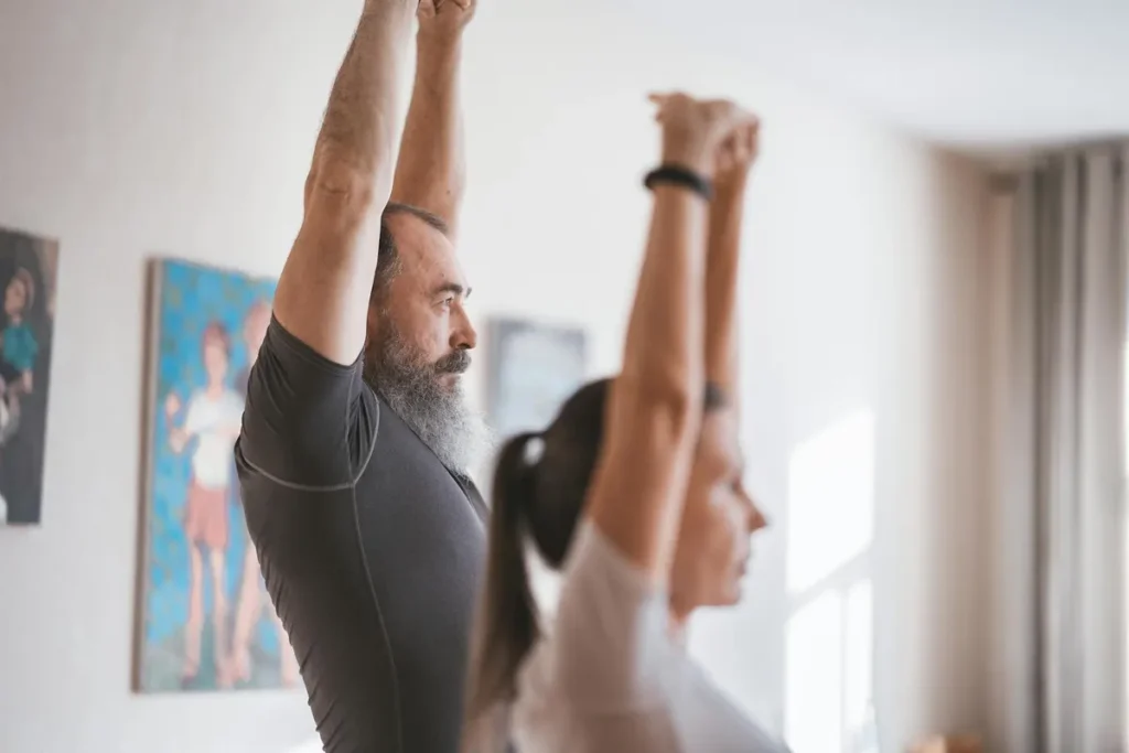 Senior couple engaging in morning yoga routine inside a bright room.