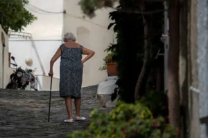 Mulher Que Caminha Enquanto Segura A Bengala Perto Da Arvore Alta 4podE_V_tAc