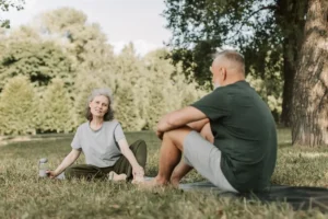 Senior couple practicing yoga and enjoying nature in a sunny park.