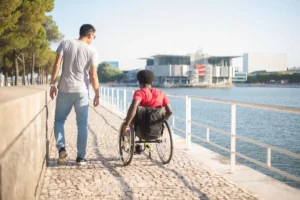 Man and friend in wheelchair strolling along the river in Portugal, showing friendship and accessibility.
