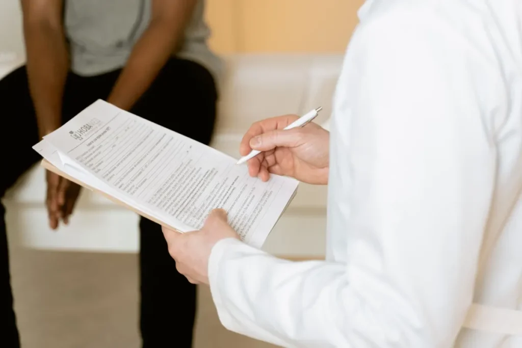 Healthcare professional reviews medical form during patient consultation in a clinic setting.