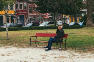 An elderly man sitting on a bench in a scenic park in Porto, Portugal.