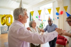 Group of seniors celebrating a birthday indoors with party hats and decorations.
