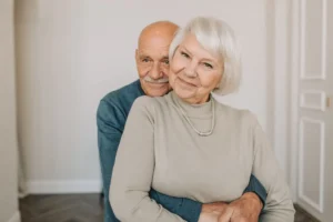 A loving elderly couple hugging indoors, showcasing warmth and happiness.